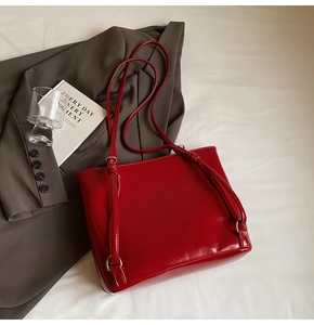 Close-up of red patent leather tote bag with glossy finish and metal hardware accents