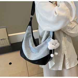 Detail view of denim and leather patchwork shoulder bag with a plush cloud charm