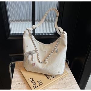 Détail du sac cabas blanc avec breloques en perles et nœud argenté élégant