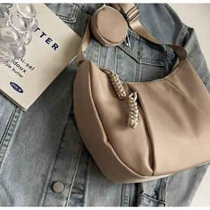 Detail of beige nylon half-moon bag with woven zipper and small coin purse on blue denim