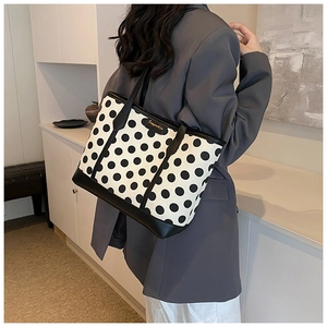 Detailed macro view of retro polka dot tote bag featuring golden metal logo and leather trim