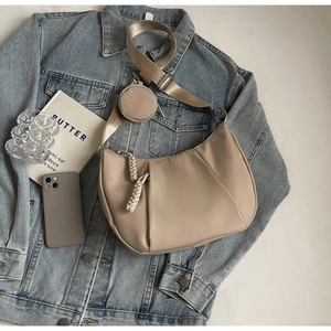 Detail view of beige crescent bag with a small round pouch and wide nylon shoulder strap