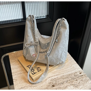 Détail du sac argenté plissé avec perles et nœud en strass au style chic Y2K