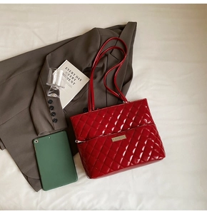 Close-up of red quilted patent leather tote bag with silver hardware and zipper details