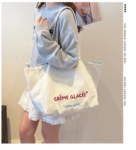 Detailed close-up of French style canvas tote bag featuring red embroidered lettering