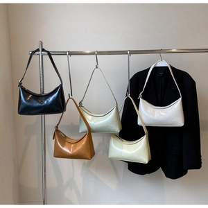 Cinco bolsos minimalistas de cuero brillante en varios colores colgados de un soporte