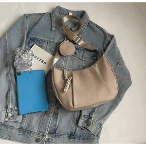 Detail of beige crescent crossbody bag with braided zipper pull and round coin purse