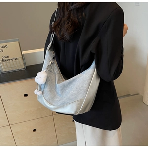 Detail of silver denim half-moon bag with fluffy cloud charm and metallic zipper