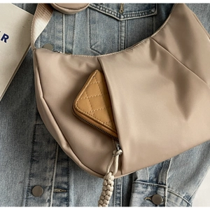 Detail of apricot crescent bag with a wallet in the front zipper pocket on denim