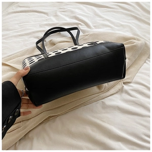 Detailed bottom view of a large black and white polka dot tote bag with a wide base