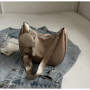 Detail of beige nylon crescent hobo bag with wide strap and round coin purse attachment