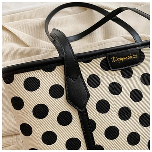 Detail of polka dot canvas tote showing black leather trim and premium brand label