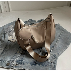 Detail of beige crescent crossbody bag with silver zipper and mini round coin purse charm