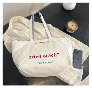 Canvas tote bag with blue stripes and red Crème Glacée embroidery in casual setting