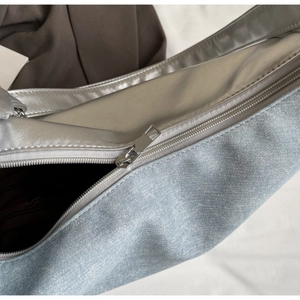 Detailed close-up of the silver hardware zipper and two-tone denim patchwork fabric
