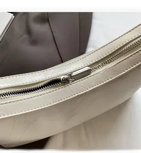 Detailed close-up of smooth silver zipper and vintage textured cream faux leather bag