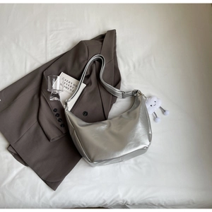 Detail of silver crescent shoulder bag with metallic finish and white cloud charm