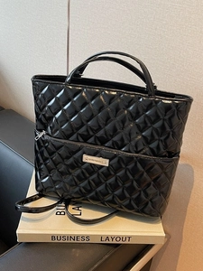 Quilted black patent leather tote bag with top handles and adjustable shoulder strap