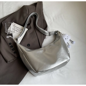 Detail view of silver hobo bag with metallic finish and white cloud plush charm