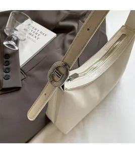Detail view of cream crescent bag featuring pebbled texture and metal buckle detail