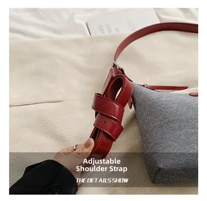 Detail view of the red leather adjustable shoulder strap with silver buckle on the bag