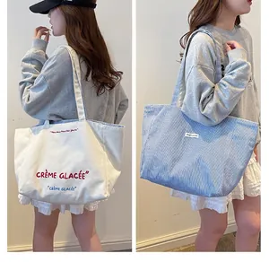 Detail of large canvas tote bag with reversible blue stripes and embroidered lettering