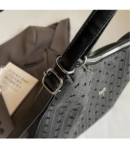 Close-up of adjustable black leather strap and silver bow detail on grey textured tote bag