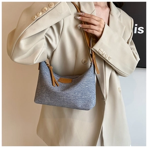 Close-up of denim underarm bag with NO FILTER leather patch and brown strap detailing