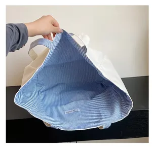 Detail view of large canvas tote bag showing striped lining and inner brand label