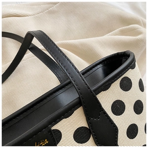 Detail of polka dot canvas tote showing black leather trim and fine stitching craftsmanship