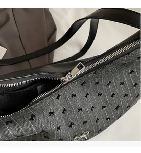 Close-up of smooth silver zipper and bow pendant on grey herringbone tote bag