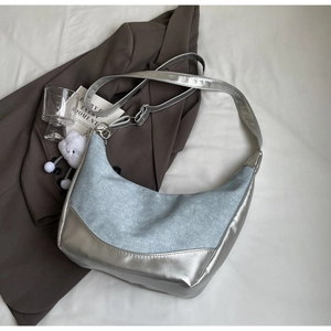 Detail of silver metallic and gray denim hobo bag with cloud charm on white fabric