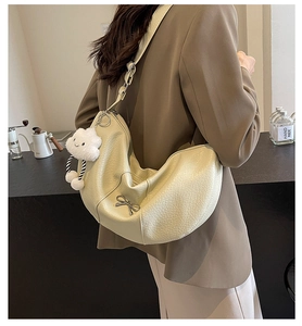 Detail of cream white half-moon crossbody bag with metal bow and cloud charm