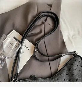 Detail of grey herringbone fabric with black bow embroidery and leather strap