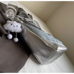 Detail of silver metallic leather and grey denim patchwork bag with a plush cloud charm