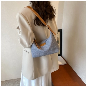 Detail of blue-grey tweed shoulder bag with brown leather strap worn by a model