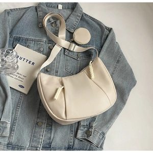 Detailed view of beige pleated crescent bag with a round coin pouch on denim jacket