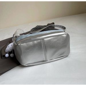 Detail of silver metallic shoulder bag with blue denim patch and fluffy cloud charm
