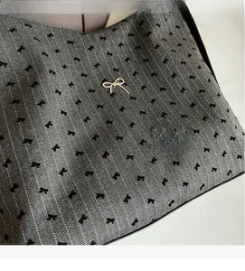 Detail of grey twill fabric with black bow patterns and gold metal bow accessory