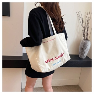 Detailed side view of large canvas tote bag with striped straps and French embroidery