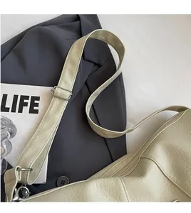 Detail of adjustable shoulder strap and lychee grain leather texture on a beige crossbody bag