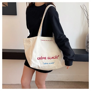 Close-up of canvas tote bag featuring red and blue French typography embroidery