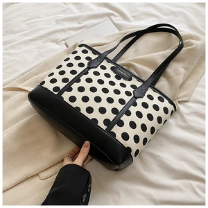 Close-up of polka dot tote bag with black leather stitching on beige corduroy fabric