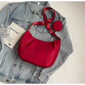 Detail of red nylon crescent bag with wide strap and round coin purse on denim jacket