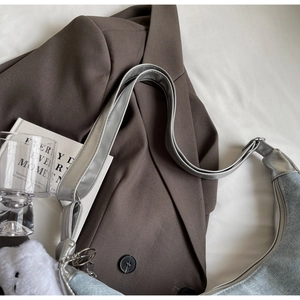 Detailed view of silver denim hobo bag with wide strap and plush bear charm