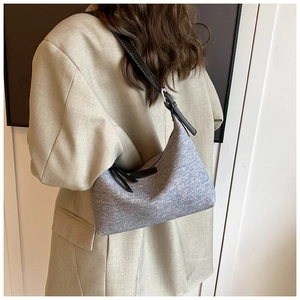 Detail of light blue hobo bag with slim black strap worn with a professional blazer