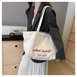 Detail of canvas tote bag featuring red and blue French embroidery on off-white fabric