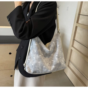 Detailed view of grey tote bag with white bow patterns and metallic bow detail