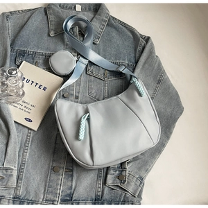 Detail of light blue crescent crossbody bag with pleated texture and round coin purse