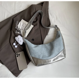 Detail of silver metallic leather and denim patchwork half-moon bag with cloud pendant